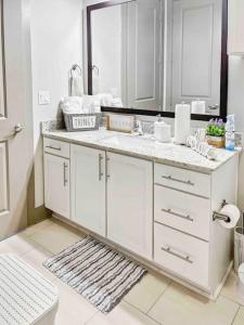 ein weißes Badezimmer mit einem Waschbecken und einem Spiegel in der Unterkunft Modern Midtown Oasis in Atlanta