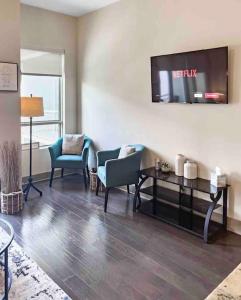 ein Wohnzimmer mit Stühlen und einem TV an der Wand in der Unterkunft Modern Midtown Oasis in Atlanta