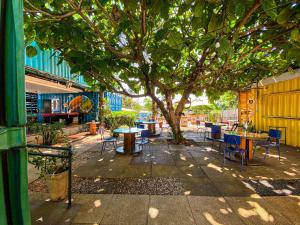 eine Terrasse mit Tischen und Stühlen unter einem Baum in der Unterkunft Tetris Container Hostel in Foz do Iguaçu