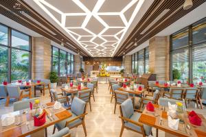 um restaurante com mesas, cadeiras e janelas em Rosa Alba Resort & Villas Tuy Hoa em Tuy Hoa