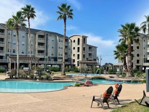 un complejo con piscina y palmeras en New Listing!! Relax by the Beach!! 2 Queen Beds, 1 Sofa Couch, Free WiFi 2 TVs, Free Parking, Pool, Hot Tub, Gym , Elevator Accessible to property, en Galveston