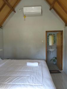 a bedroom with a white bed and a window at Sunset Point Kembang Kuning in Tetebatu