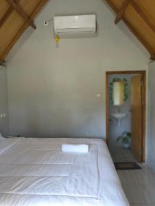 1 dormitorio con cama blanca y ventana en Sunset Point Kembang Kuning en Tetebatu