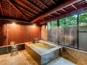 Habitación con ventanas y baño grande con bañera grande. en Hoshi en Komatsu