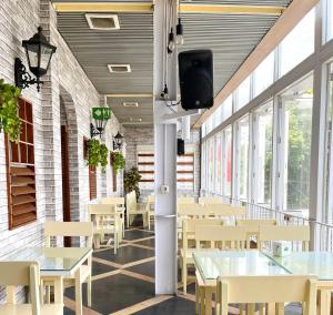 a dining room with tables and chairs and windows at Hotel Wisata Niaga Campus in Purwokerto