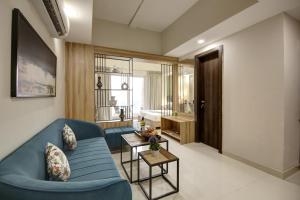 a living room with a blue couch and a bedroom at Saltstayz Premier - Golf Course Extension Road in Gurgaon