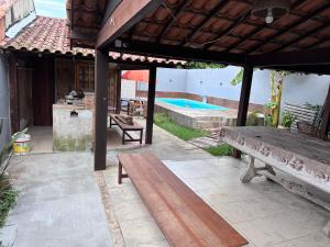 eine Terrasse mit einer Bank und einem Pool in der Unterkunft Casa 4 quartos com piscina Grussai in São João da Barra
