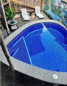 a small blue swimming pool with chairs around it at Hostel Rústico MarAbi in Tarcoles