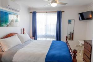 Cette chambre comprend un lit avec des rideaux bleus et une télévision. dans l'établissement Shabby Chic Shack - 2 bedroom Beach Cottage, à Yanchep