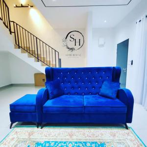 eine blaue Couch in einem Wohnzimmer mit einer Treppe in der Unterkunft KLIA SomeHouse Homestay in Banting