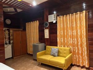un soggiorno con divano giallo e tende di Theresa's Pension House a San Vicente