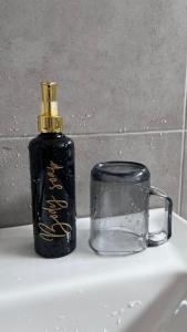 eine Flasche Öl neben einer Tasse auf einem Waschbecken in der Unterkunft KLIA SomeHouse Homestay in Banting