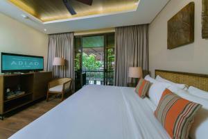 a bedroom with a large white bed and a tv at Balai Adlao in El Nido