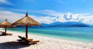dos sillas y sombrillas en una playa con el océano en Homestay T&T - Căn hộ gia đình, en Da Nang