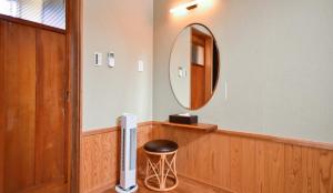 a bathroom with a circular mirror and a stool at Kamegawa Onsen HATAGO Yuyu in Beppu