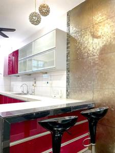una cocina con armarios rojos y 2 taburetes negros en CozyHouse 4ROOM 4BATH ROOM 8PAX@Near BM Icon city, en Bukit Mertajam