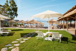 a group of chairs and tables with umbrellas on the grass at Bellazure Hotel in Akyarlar