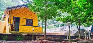 a small yellow building with a man standing in front of it at STAYMAKER River Wood Residency in Dandeli