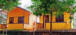 una pequeña casa amarilla y azul frente a un edificio en STAYMAKER River Wood Residency, en Dandeli