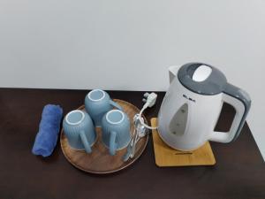 a tea kettle and three blue cups on a table at Suria Paradise Lodge in Ranau
