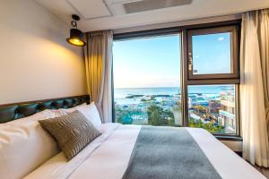 a bedroom with a bed and a large window at Marevo Beach Hotel in Jeju