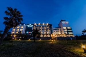 a building at night with a palm tree in the foreground at Marevo Beach Hotel in Jeju
