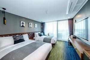 Habitación de hotel con 2 camas y TV de pantalla plana. en Marevo Beach Hotel en Jeju