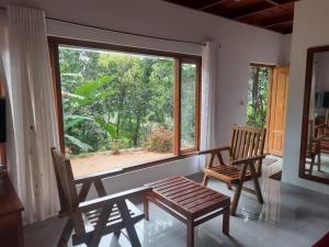 ムンナルにあるkurinjiyil Farm Stay Munnarの椅子2脚と大きな窓が備わる客室です。