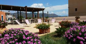 a patio with chairs and flowers with mountains in the background at Hotel A Cannata in Santa Marina Salina