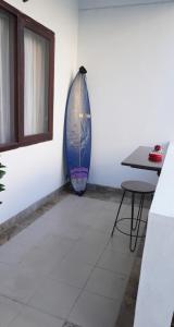 una tabla de surf apoyada en una pared junto a una mesa en Balian Surf Club, en Legian