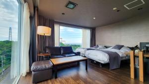 a bedroom with a bed and a chair and a window at Business Resort Kyuan in Oita