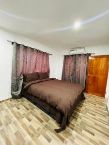 Schlafzimmer mit einem Bett und Vorhängen sowie Holzböden in der Unterkunft Blissful Calm in Nadi