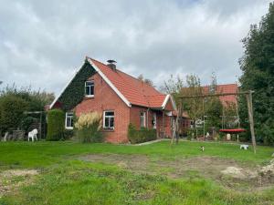 a red brick house with two dogs in front of it at Lüttje Huus Wirdum in Wirdum