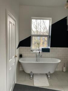 a white bath tub in a bathroom with a window at Entire boutique mill cottage in Elland