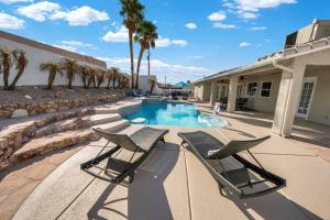 a swimming pool with two lounge chairs next to a building at BOHO House - Pool, Spa, Boat Parking, Central in Lake Havasu City