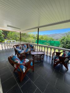 eine Veranda mit Stühlen, Tischen und einem weißen Dach in der Unterkunft Akivai Lodge - Maison de vacance Ua-Pou Marquises in Hakamui