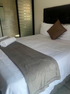 a large bed with white sheets and a gray blanket at 367 @ The Blyde in Pretoria
