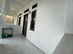 a hallway with a white wall and a door at OYO Life 93154 White Kos Jenggala in Tanjung