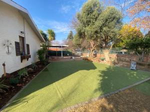 um quintal com um relvado verde em frente a uma casa em Aloe Guest Rooms em Bloemfontein