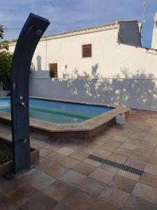 una piscina accanto a un muro bianco con un palo nero di Cortijo Rural El Salado a Castillo de Locubín