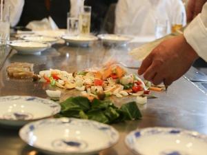 a chef preparing a salad on a table with plates at LiVEMAX RESORT Aki Miyahama Onsen in Hatsukaichi