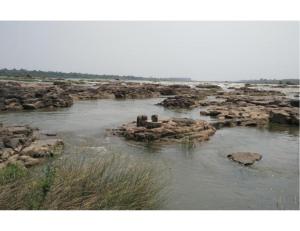 a body of water with rocks in the water at Hotel Sanginee, Maheshwar in Maheshwar