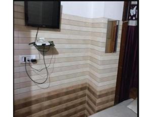 a bathroom with a shower with a television on a wall at Hotel Sanginee, Maheshwar in Maheshwar