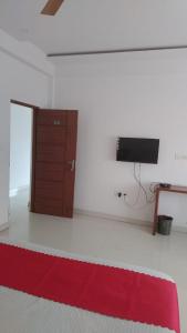 a room with a red rug and a tv on a wall at PPH Living B S K in Bengaluru
