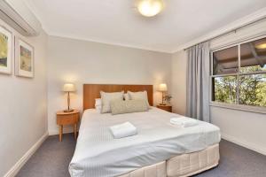 um quarto com uma grande cama branca e uma janela em Villa 2br Madeira Villa located within Cypress Lakes Resort em Pokolbin