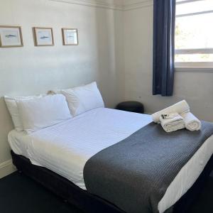 a bedroom with a bed with a phone on it at Beachside Budget Rooms in Kiama