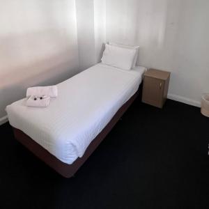 uma cama branca com uma toalha em cima em Beachside Budget Rooms em Kiama