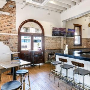 a bar in a restaurant with tables and stools at Beachside Budget Rooms in Kiama