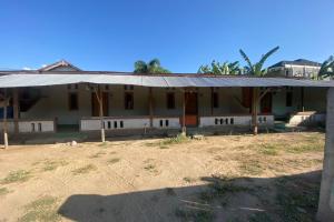 uma casa com um telhado de estanho num campo em OYO Life 93153 Kos Jenggala em Tanjung