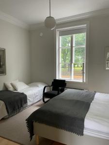 a bedroom with two beds and a chair and a window at Old Turku Family Apartment in Turku